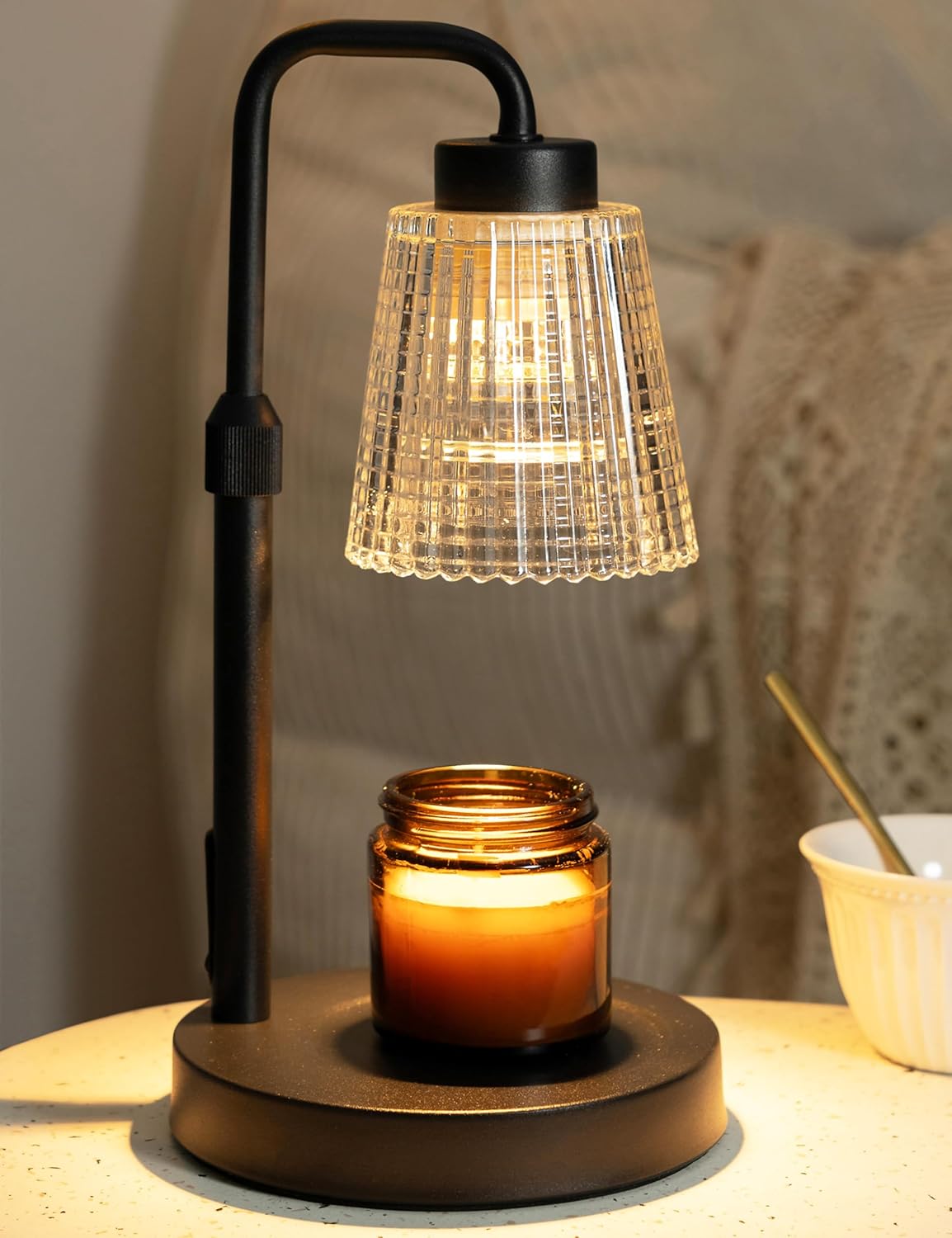 Candle warmer lamp with metal base and glass shade over a jar candle